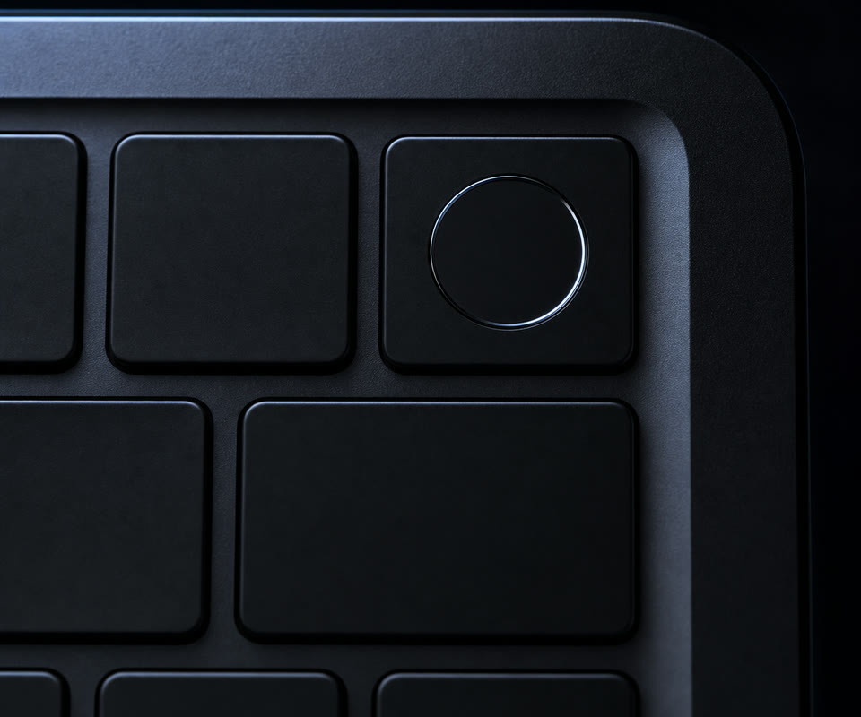 Macro of a MacBook Touch ID key, rim-lit in the dark.